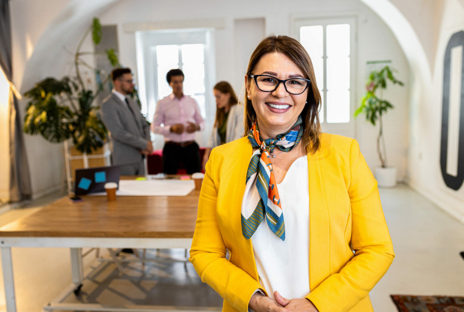 Portrait of smiling businesswoman in office with her colleagues